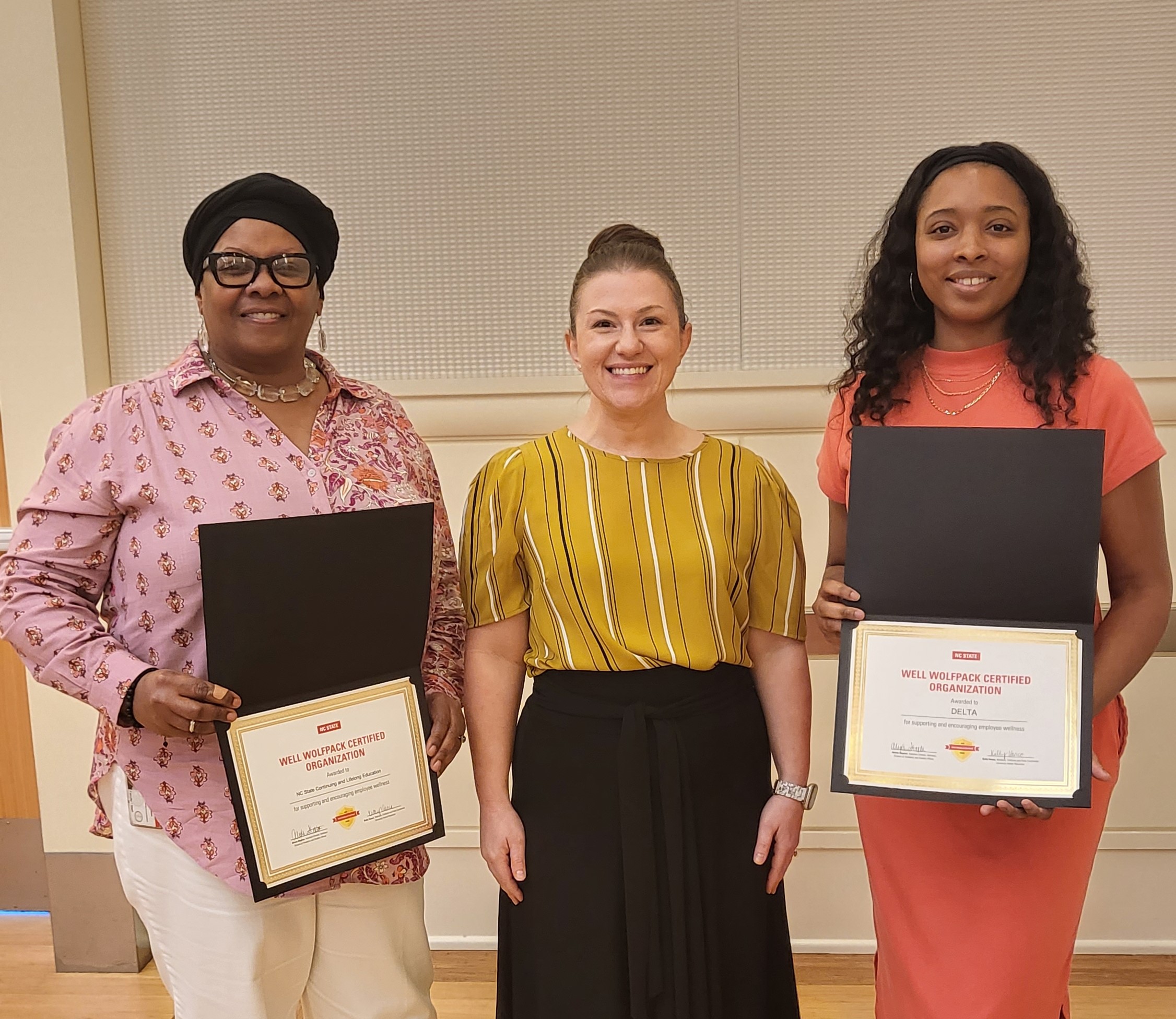 Three women pose together after winning a wellness award.