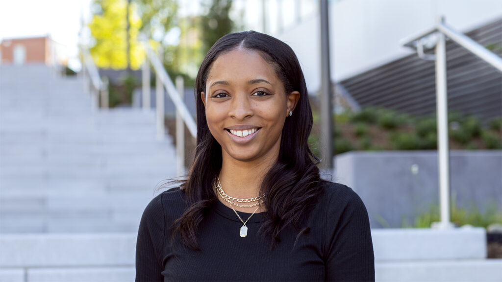 a woman standing outdoors smiling in a head shot